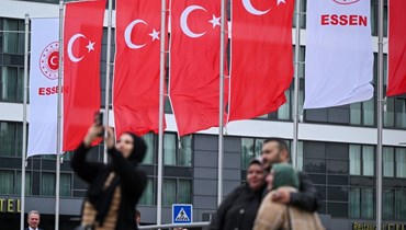ناخبون أتراك مقيمون في ألمانيا يلتقطون صورا لأنفسهم أمام أعلام تركية رفعت خارج مركز اقتراع في إيسن غرب ألمانيا (23 أيار 2023، أ ف ب).