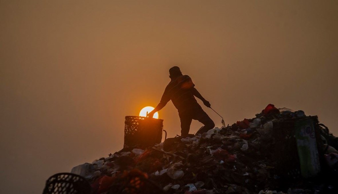 رجل يجمع أشياء يمكن إعادة بيعها من شاحنات القمامة في إندونيسيا (أ ف ب).