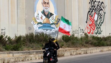 شابان على دراجة نارية يرفعان العلم الإيراني مقابل الجدار الفاصل مع الحدود الفلسطينية جنوب لبنان (أ ف ب).