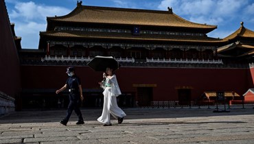 امرأة تمر بجوار مدخل المدينة المحرمة في بيجينغ (7 حزيران 2023، أ ف ب). 