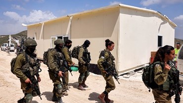 جنود إسرائيليون يسيرون خارج مبنى قيد الإنشاء في الضفة الغربية المحتلة (أ ف ب). 