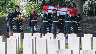 جنود يحملون نعش أحد الجنود الكنديين الثلاثة الذين لقوا حتفهم خلال الحرب العالمية الأولى، خلال جنازة في مقبرة بريطانية في لوزاغوهيل شمال فرنسا (8 حزيران 2023، أ ف ب). 