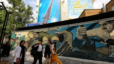 مرور نساء أمام لوحة جدارية تظهر خلفها صورة لصاروخ "فتاح" الذي، في طهران (أ ف ب). 