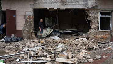  أحد السكان يزيل حطام متجر دمّر بعد قصف روسي في خيرسون  (أ ف ب). 