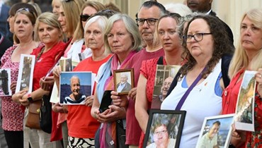 أعضاء من كوفيد-19 بيريفد فاميليز فور جاستيس حملوا صورا لأقارب ماتوا خلال الوباء، بينما تظاهروا خارج مكان انعقاد جلسات التحقيق بالجائحة غرب لندن (13  حزيران 2023، أ ف ب).