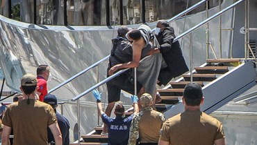 أشخاص يحملون أحد الناجين في ميناء بلدة كالاماتا، بعد غرق قارب المهاجرين قبالة اليونان (14 حزيران 2023، أ ف ب). 