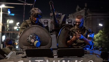 عنصران من مجموعة فاغنر يستقلّان مركبة عسكرية تحمل لافتة كُتب عليها "الأخ" في روستوف-أون-دون، في وقت متأخر من مساء السبت (24 حزيران 2023 - أ ف ب).