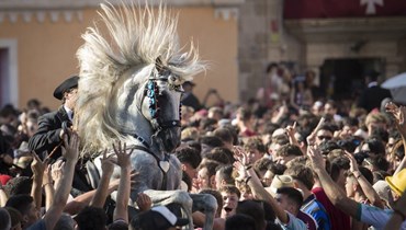حصان يشبّ وسط الحشد خلال كاراغول دس بورن، في مهرجان سان جون التقليدي في مدينة سيوتاديلا في مينوركا بإسبانيا، عشية عيد القديس يوحنا (23 حزيران 2023، أ ف ب).