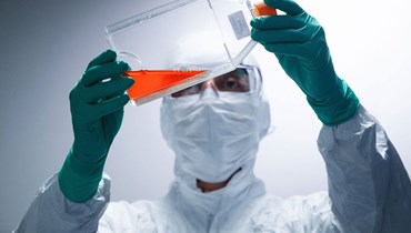 فنّي في شركة "سانوفي" للصناعات الدوائية يتفحّص زجاجة تحتوي على كاشف قبل إجراء اختبارات اللقاح (أ ف ب).