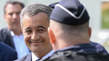 وزير الداخلية الفرنسي جيرالد دارمانان يتحدث الى شرطي خارج مركز الشرطة في إيفري كوركورون جنوب باريس (30 حزيران 2023، أ ف ب).