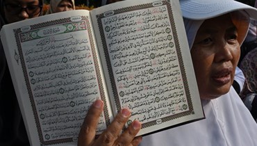 سيدة إندونيسية ترفع نسخة من القرآن الكريم (أ ف ب).