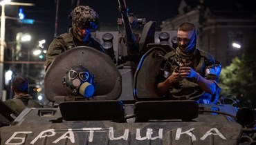 عنصران من مجموعة فاغنر يستقلّان مركبة عسكرية تحمل لافتة كُتب عليها "الأخ" في روستوف-أون-دون، في وقت متأخر من مساء السبت (24 حزيران 2023 - أ ف ب).