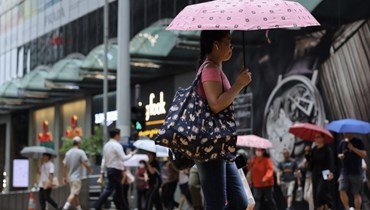 امرأة تستخدم مظلّة للاحتماء من المطر في هونغ كونغ في 3 تموز 2023 (أ ف ب). 
