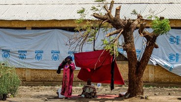 أشخاص جلسوا في الظل بجانب شجرة في مخيم للنازحين في الصوار شمال ود مدني (22 حزيران 2023، أ ف ب). 