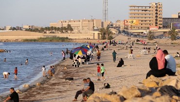 ليبيون يستمتعون بيومهم على شاطئ طرابلس خلال موجة حر (6 تموز 2023، أ ف ب). 