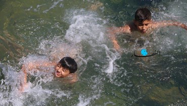 فتيان يمارسون هواية السباحة هرباً من موجة الحرّ (حسن عسل).