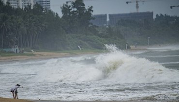 اشخاص يشاهدون أمواجا عاتية على شاطئ البحر مع اقتراب الإعصار تاليم، في بواو بمقاطعة هاينان جنوب الصين (17 تموز 2023/ أ ف ب).