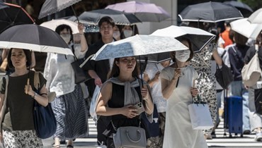أشخاص يرفعون مظلّة للحماية من أشعّة الشمس وسط درجات حرارة مرتفعة في طوكيو (تعبيرية- "أ ف ب").