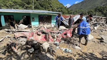أشخاص يقفون بالقرب من سيارة مدمرة بعد انهيار أرضي في بلدية كويتامي بمقاطعة كونديناماركا في كولومبيا (18 تموز 2023، أ ف ب).