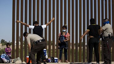 عناصر حرس الحدود الأميركية يقومون بتفتيش المهاجرين من غواتيمالا، على الحدود بين الولايات المتحدة والمكسيك في يوما، ولاية أريزونا (12 أيار 2021 - أ ف ب).