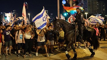 شرطي اسرائيلي بمواجهة متظاهرين تجمعوا على طريق سريع في تل أبيب خلال احتجاج على مشروع قانون الإصلاح القضائي (20 تموز 2023، أ ف ب).