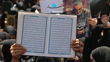 متظاهرة ترفع نسخة من القرآن الكريم في الضاحية الجنوبية لبيروت خلال اعتصام احتجاجيّ تنديداً بالمساس به (حسن عسل). 