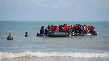 مهاجرون يجلسون على متن قارب قابل للنفخ قبل محاولتهم العبور بشكل غير قانوني إلى بريطانيا (أ ف ب). 