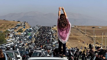 صورة نُشرت على "تويتر" تُظهر امرأة تقف فوق سيارة بينما يشق الآلاف طريقهم نحو مقبرة في مسقط رأس مهسا أميني في إقليم كردستان، غرب إيران (26 ت1 2022 - أ ف ب).