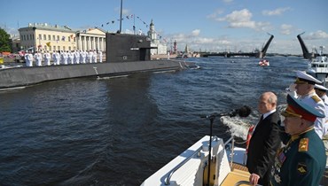بوتين، الى جانبه شويغو والقائد العام للبحرية الروسية الأدميرال نيكولاي يفمينوف، خلال عرض يوم البحرية في سان بطرسبرج (30 تموز 2023، أ ف ب). 