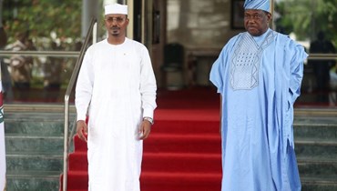 ديبي (إلى اليسار) يستقبله امين سر حكومة الاتحاد النيجيري  جورج أكومي، خلال اجتماع قمة لإيكواس في أبوجا (30 تموز 2023، أ ف ب).