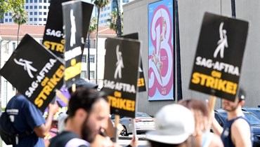 أعضاء نقابة كتّاب السيناريو ونقابة الممثّلين يشاركون في الإضراب خارج استوديو "وارنر بروس" في بوربانك، كاليفورنيا (26 تموز 2023 - أ ف ب).