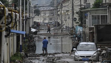 سكان ينظفون شارعا في أعقاب فيضانات في قرية بعد هطول أمطار غزيرة في بيجينغ (3 آب 2023، أ ف ب).