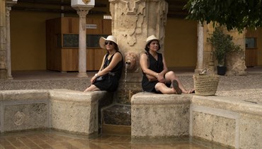 سياح جلسوا بالقرب من نافورة في قرطبة جنوب إسبانيا (8 آب 2023، أ ف ب).