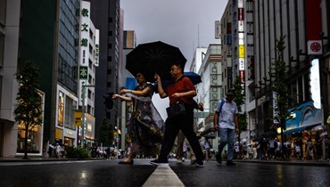 مشاة احتموا بمظلاتهم من المطر في منطقة جينزا بطوكيو (13 آب 2023، أ ف ب).