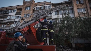 فرق الإنقاذ تعمل خارج مبنى سكني متضرّر، بعد ضربات صواريخ روسية في بوكروفسك، منطقة دونيتسك (7 آب 2023 - أ ف ب).