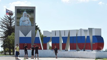 لافتة كُتب عليها "ماريوبول" مرسومة بألوان العلم الروسي وفوقها "أيقونة والدة الإله"، في ماريوبول (16 آب 2023 - أ ف ب).