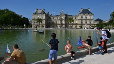 أطفال يلعبون بقوارب مائية قبالة قصر لوكسمبورغ في حدائق لوكسمبورغ في باريس (17 آب 2023، أ ف ب). 