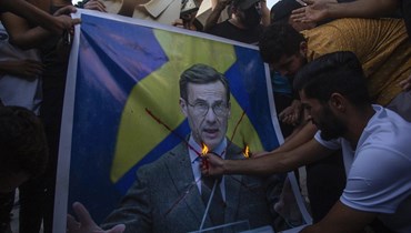 عراقيون يحرقون صورة لرئيس الوزراء السويدي أولف كريسترسون خلال احتجاج في ساحة التحرير في بغداد (20 تموز 2023، أ ف ب).