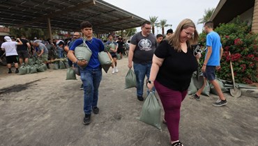سكان يحملون أكياس رمل في موقف سيارات تابع لمكتبة في إنديو، بينما يتجه الإعصار هيلاري شمالا نحو جنوب كاليفورنيا (19 آب 2023، أ ف ب). 