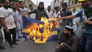 أنصار للحزب الإسلامي المتطرف "تحريك لبيك باكستان" يحرقون صورة للعلم السويدي خلال مسيرة في كراتشي للتنديد بحرق المصحف  (7 تموز 2023، أ ب). 