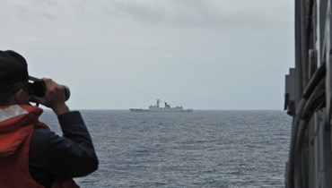 بحار من البحرية التايوانية يراقب سفينة حربية تابعة للبحرية الصينية. (أ ف ب)