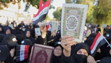 عراقيون يرفعون نسخا من المصحف خلال احتجاج في بغداد (22 تموز 2023، أ ب).