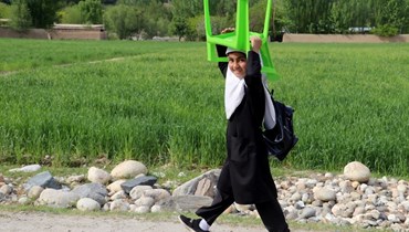 تلميذة تحمل كرسيّاً في طريقها إلى المنزل في منطقة فيزاباد، ولاية بدخشان (9 نيسان 2023 - أ ف ب).