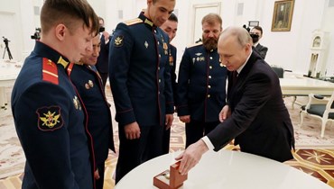 بوتين (الى اليمين) ينظر إلى ساعة خلال اجتماع بطاقم دبابة أليوشا تي 80 في موسكو (24 آب 2023ـ أ ف ب).