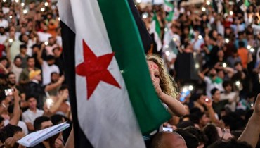 فتاة ترفع علم المعارضة السورية، خلال تظاهرة في مدينة إدلب دعماً للاحتجاجات في السويداء (أ ف ب). 