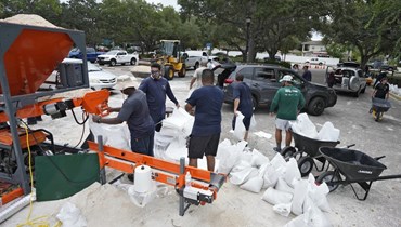عناصر تابعون لإدارة الحدائق والترفيه في تامبا بولاية فلوريدا، يساعدون السكان في الحصول على أكياس الرمل (28 آب 2023، أ ب).