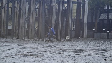 رجل يشق طريقه وسط سيول في شارع بالقرب من مرسى ستينهاتشي في ستينهاتشي بفلوريدا بعد وصول الإعصار إيداليا إلى اليابسة (30 آب 2023، أ ف ب).