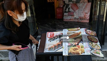امرأة تنظر إلى قائمة مطعم ياباني بالقرب من السفارة اليابانية في بيجينغ (أ ف ب). 