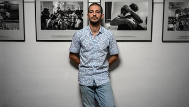المصور الفرنسي مايكل بونيل يقف في موقع المعرض الخاص به خلال مهرجان "فيزا" (أ ف ب).