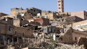 مئذنة مسجد تقف خلف المنازل المدمّرة خلال زلزال المغرب (أ ف ب).